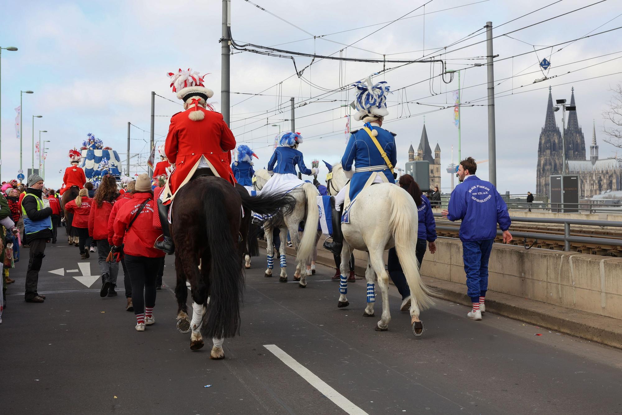 Funken reiten während des Rosenmontagszuges mit Pferden über die Deutzer Brücke.