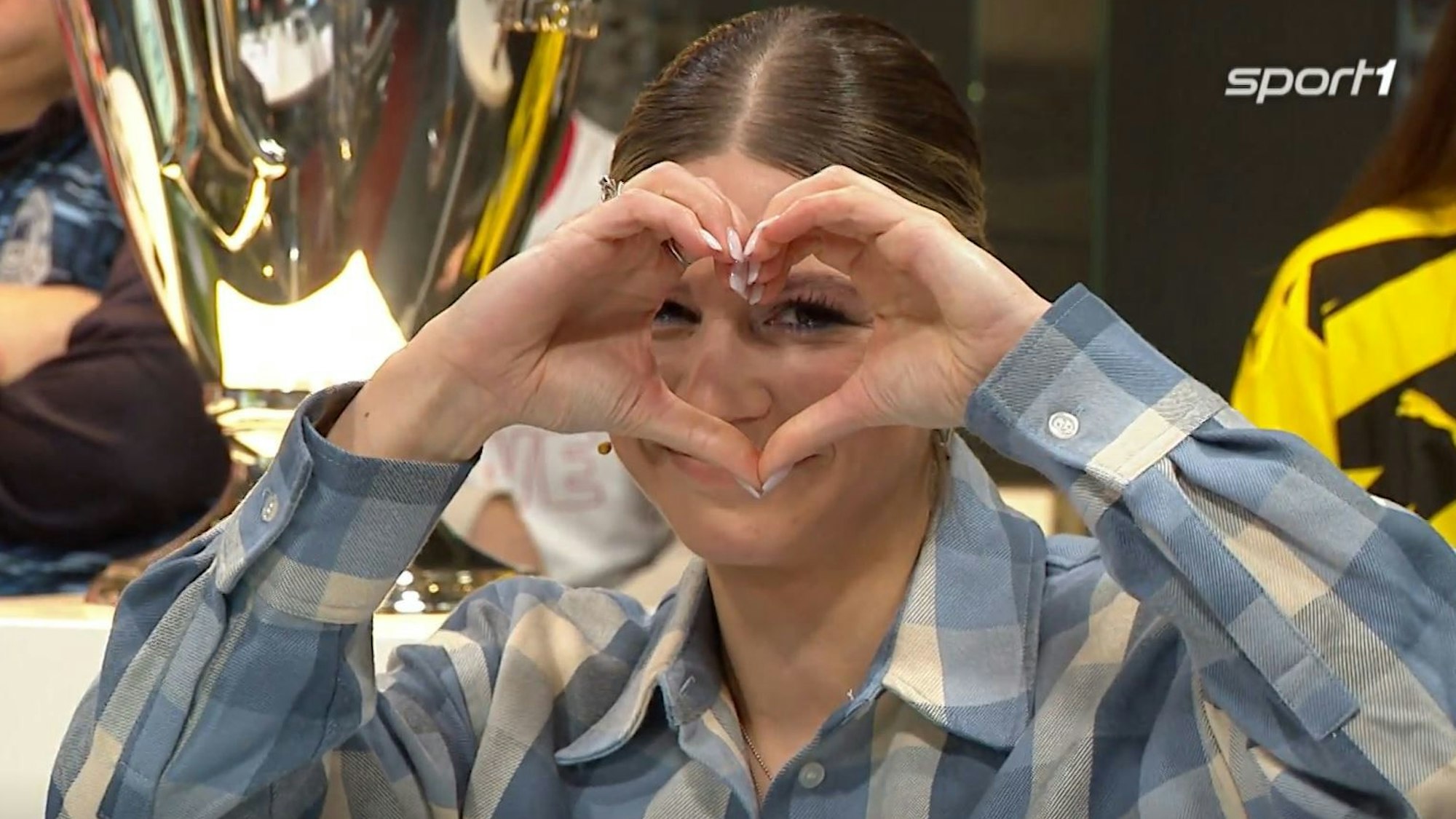 Sport1-Moderatorin Jana Wosnitza bildet mit ihren Händen ein Herz.