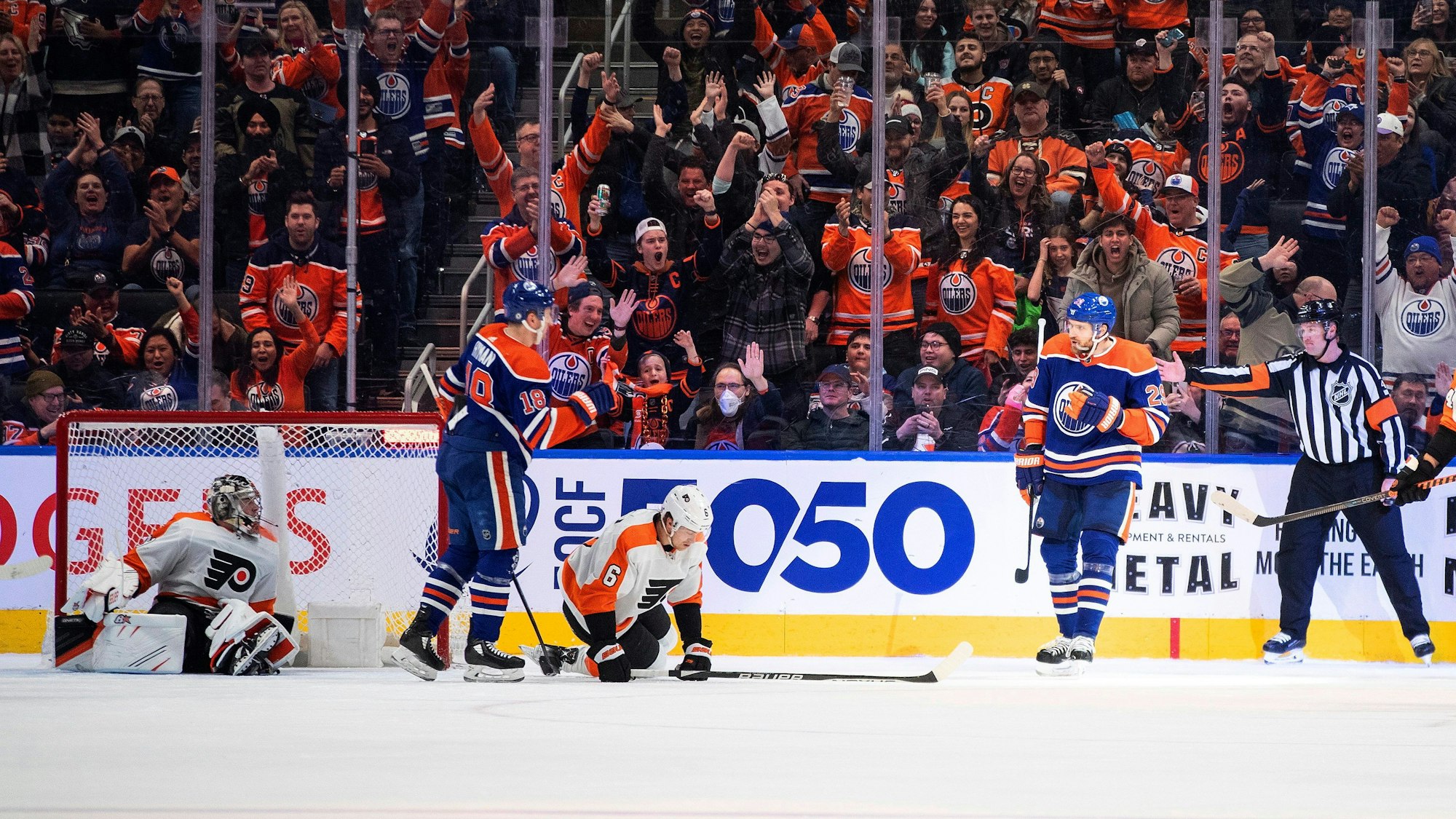 Torwart Carter Hart (l.) und Travis Sanheim (3.v.l.) von den Philadelphia Flyers liegen am Boden, während Zach Hyman (2.v.l.) und Leon Draisaitl (2v.r.) von den Edmonton Oilers ein Tor feiern.