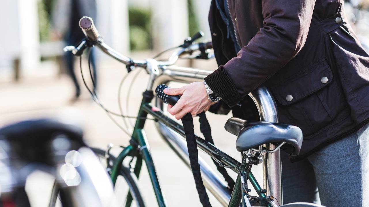 Ein Mann schließt ein Fahrradschloss auf.
