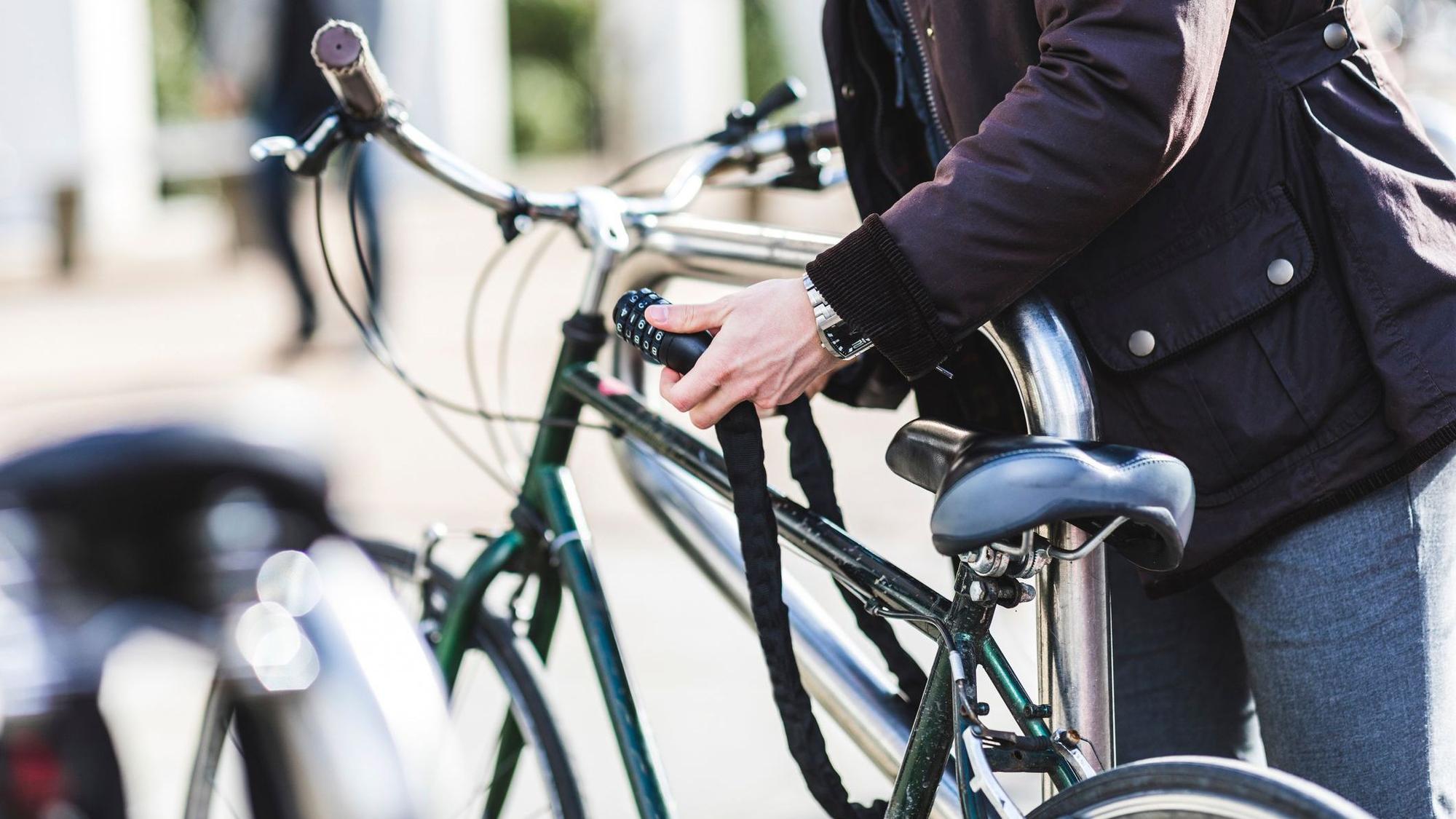 Ein Mann schließt ein Fahrradschloss auf.