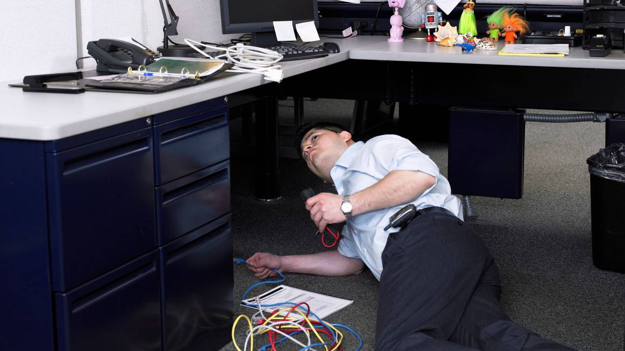 Mann unter Schreibtisch versucht Kabel anzuschließen