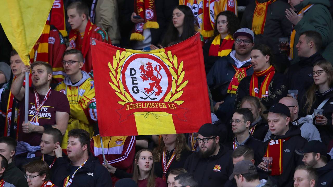 Eishockey-Fans der DEG halten ein Banner mit dem Schriftzug und Logo der DEG hoch.