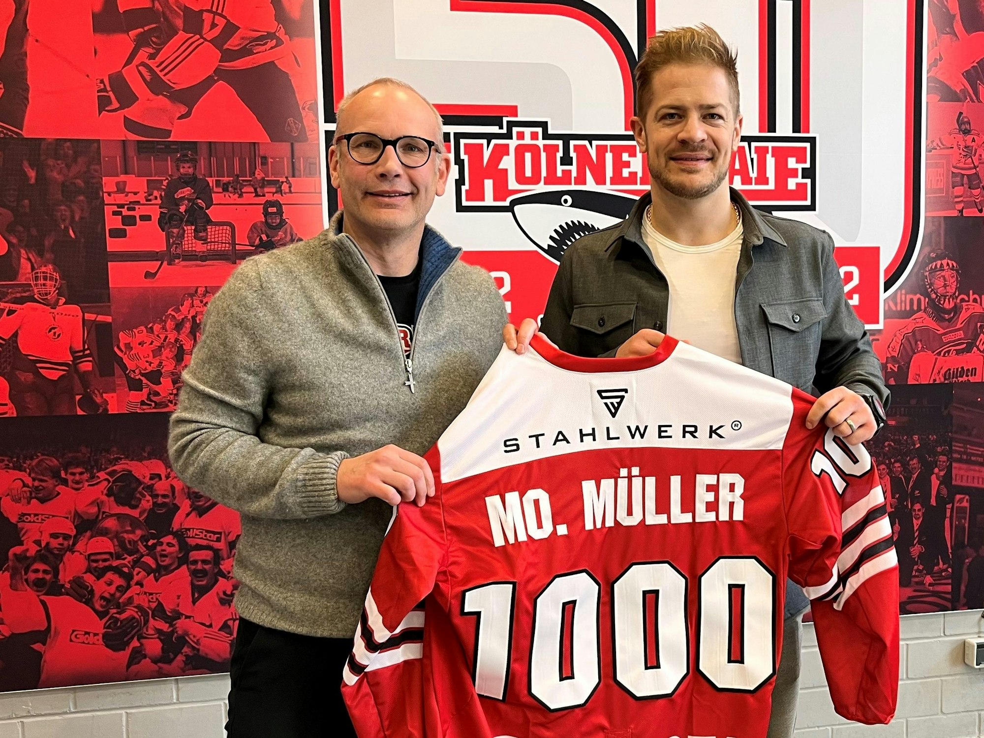Mirko Lüdemann und Moritz Müller zeigen das Haie-Trikot mit der 1000.