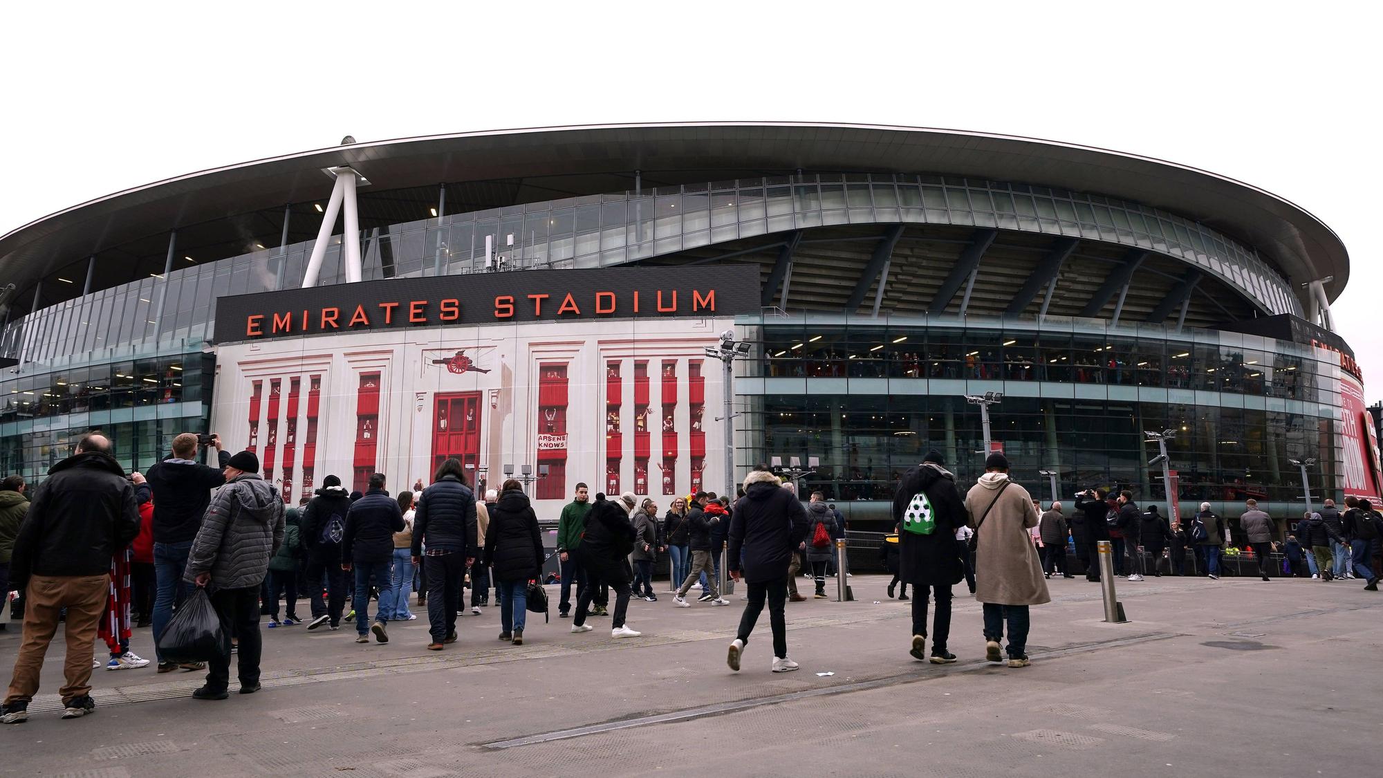 Das Emirates Stadium ist seit 2006 die Heimstätte des Premier-League-Vereins FC Arsenal. Das Foto zeigt das Stadion von außen am 11. Februar 2023, dem Tag des Arsenal-Heimspiels gegen Brentford. Fans überqueren den Vorplatz des Stadiums in Winterkleidung.