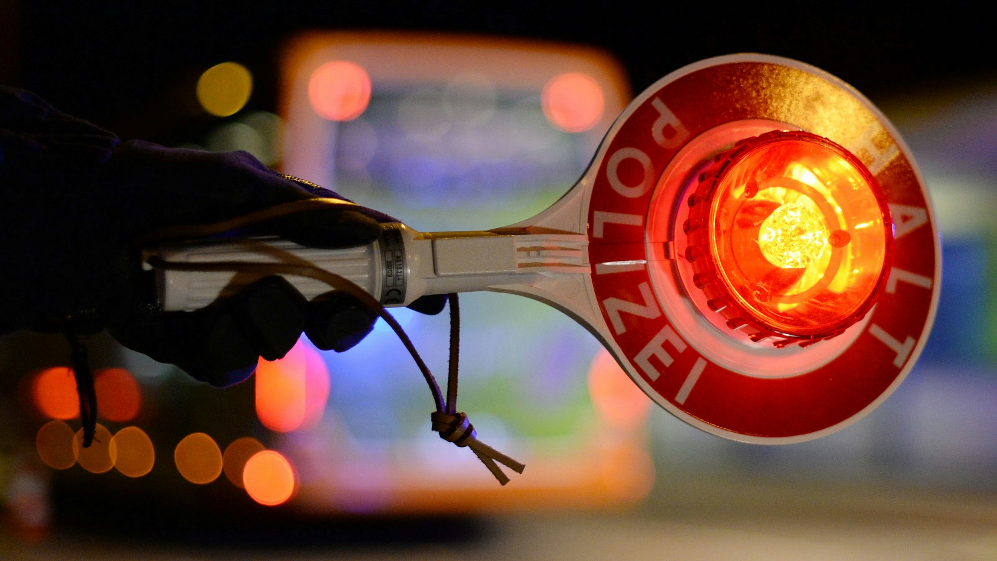 Ein Beamter hält dabei eine beleuchtete Haltekelle.