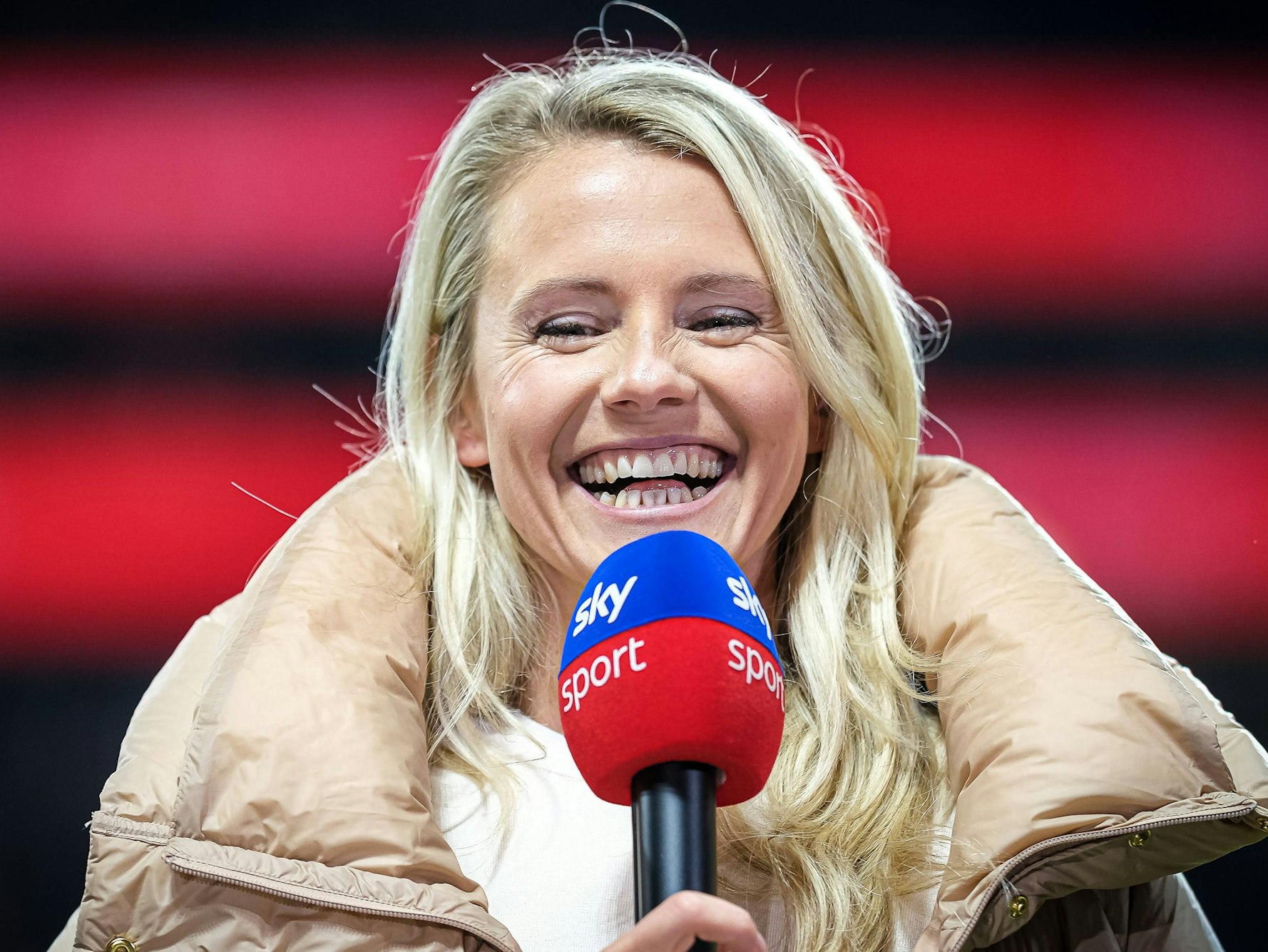 Julia Simic steht mit einem Sky-Mikrofon am Spielfeldrand.