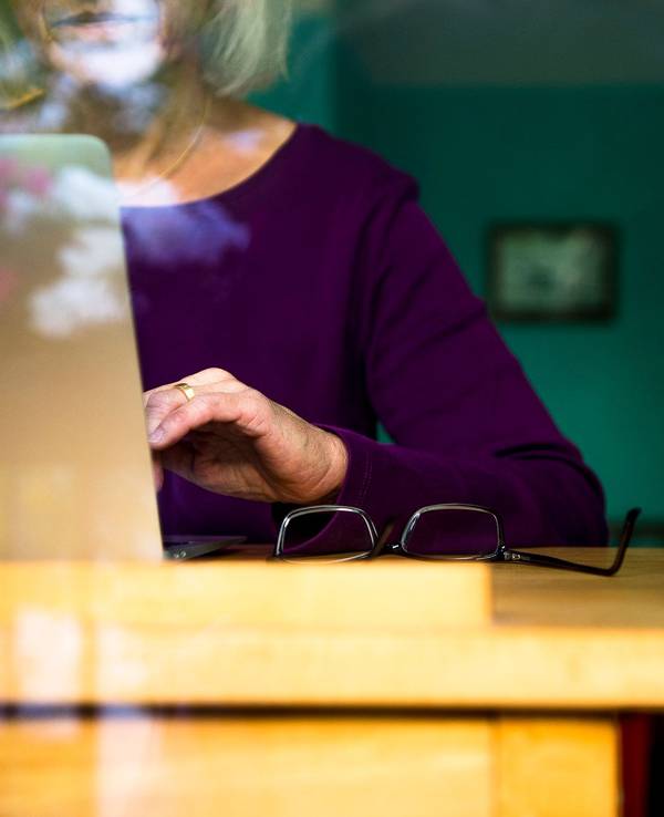 Eine Frau sitzt zuhause an einem Schreibtisch und arbeitet an einem Laptop.