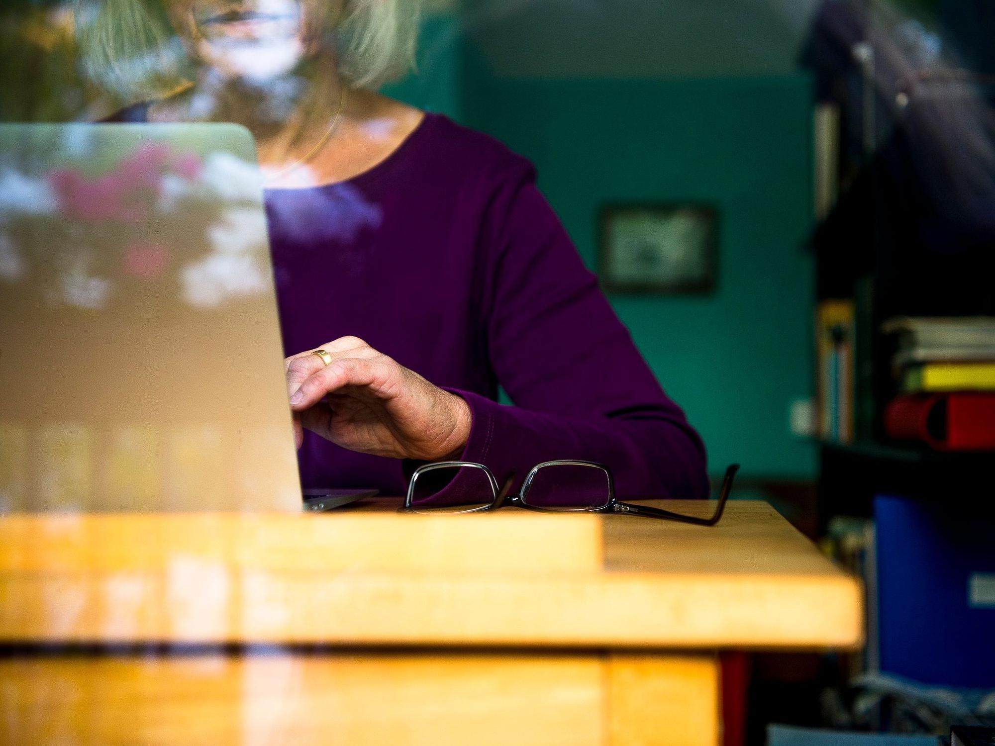 Eine Frau sitzt zuhause an einem Schreibtisch und arbeitet an einem Laptop.
