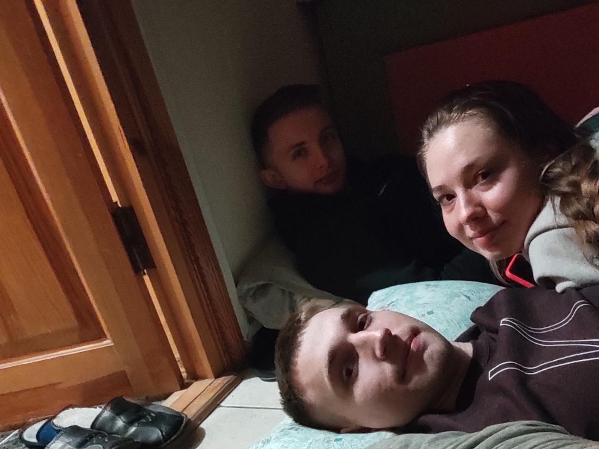 Auf dem Bild sieht man drei junge Menschen, die nebeneinander auf dem Boden liegen und in die Kamera schauen.