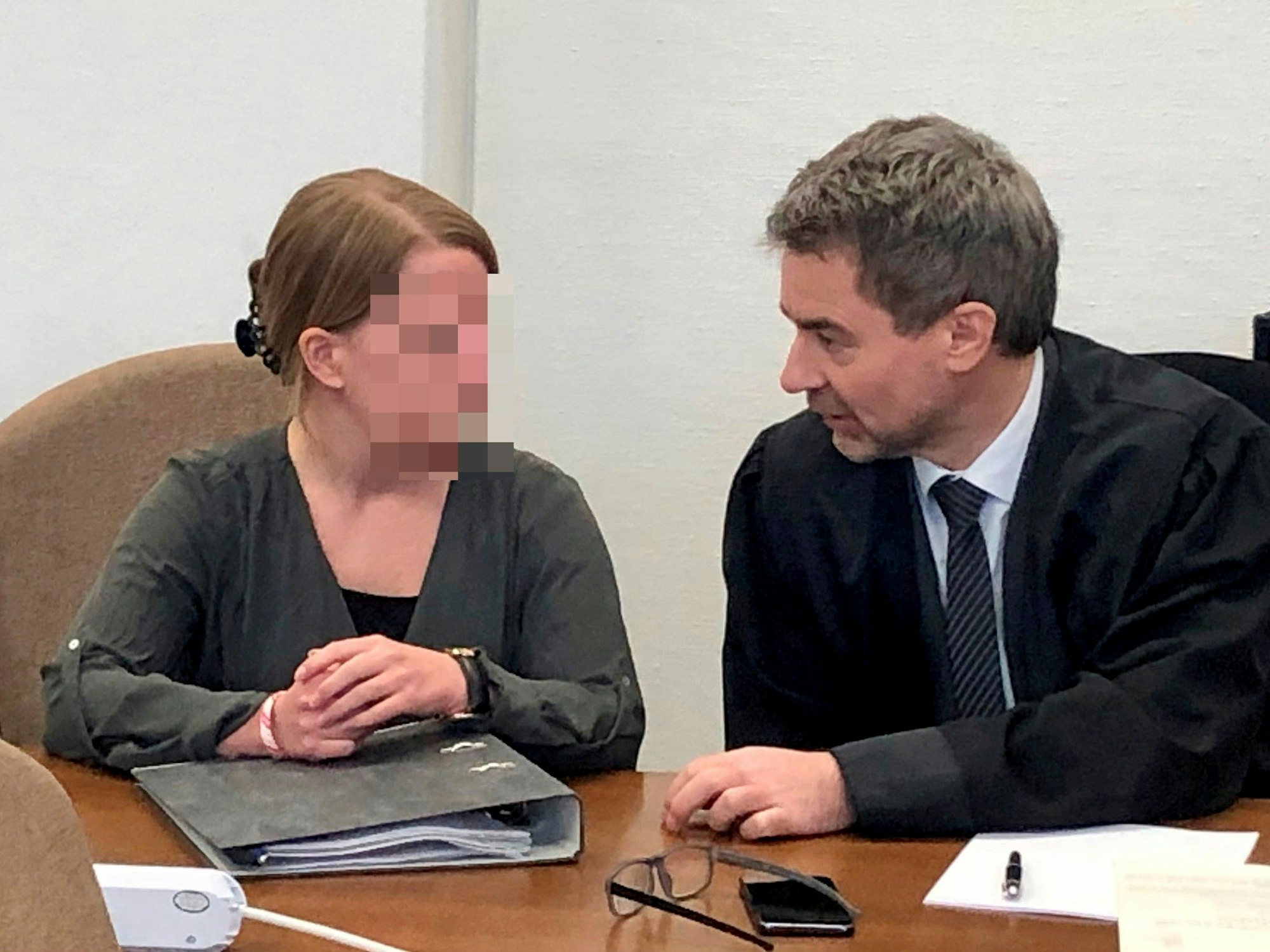 Eine Frau sitzt neben ihrem Anwalt in einem Gerichtssaal.