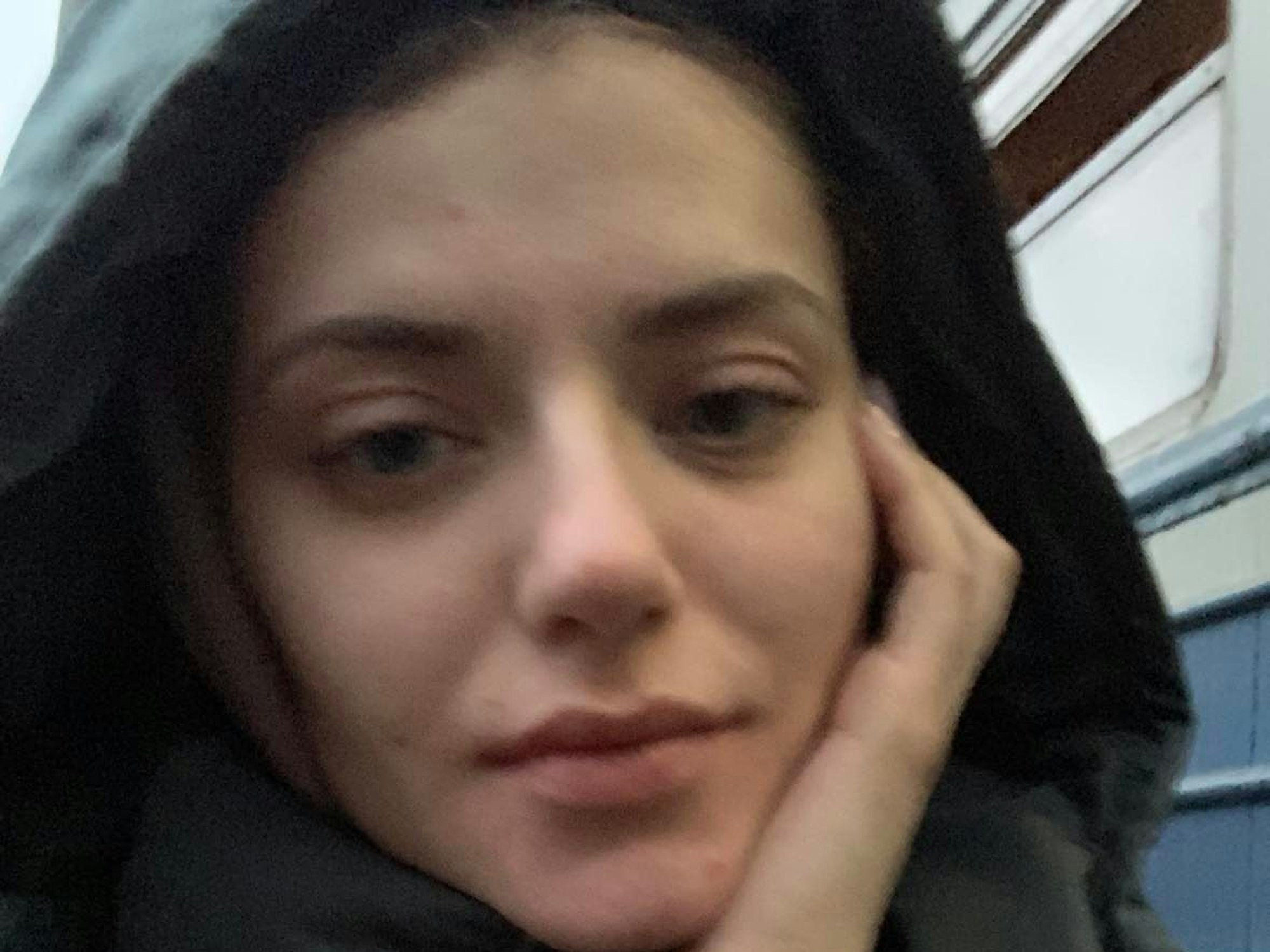 Eine junge Frau nimmt ein Selfie auf. Sie guckt müde in die Kamera.