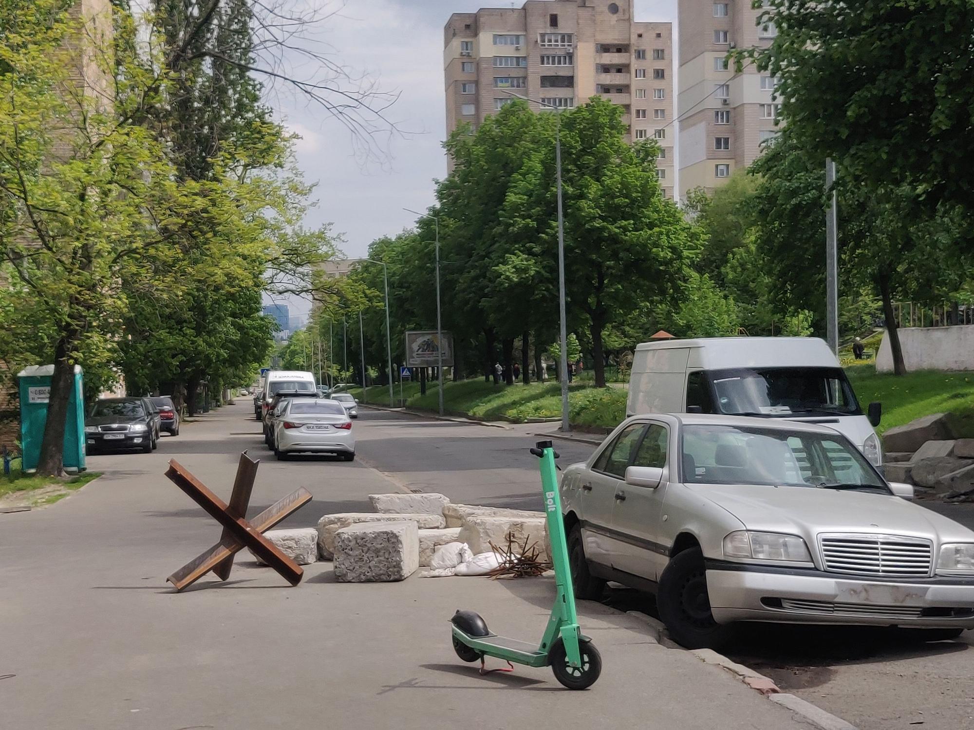 Steinklötze liegen auf dem Boden, neben einer Straße. Davor steht ein E-Scooter.