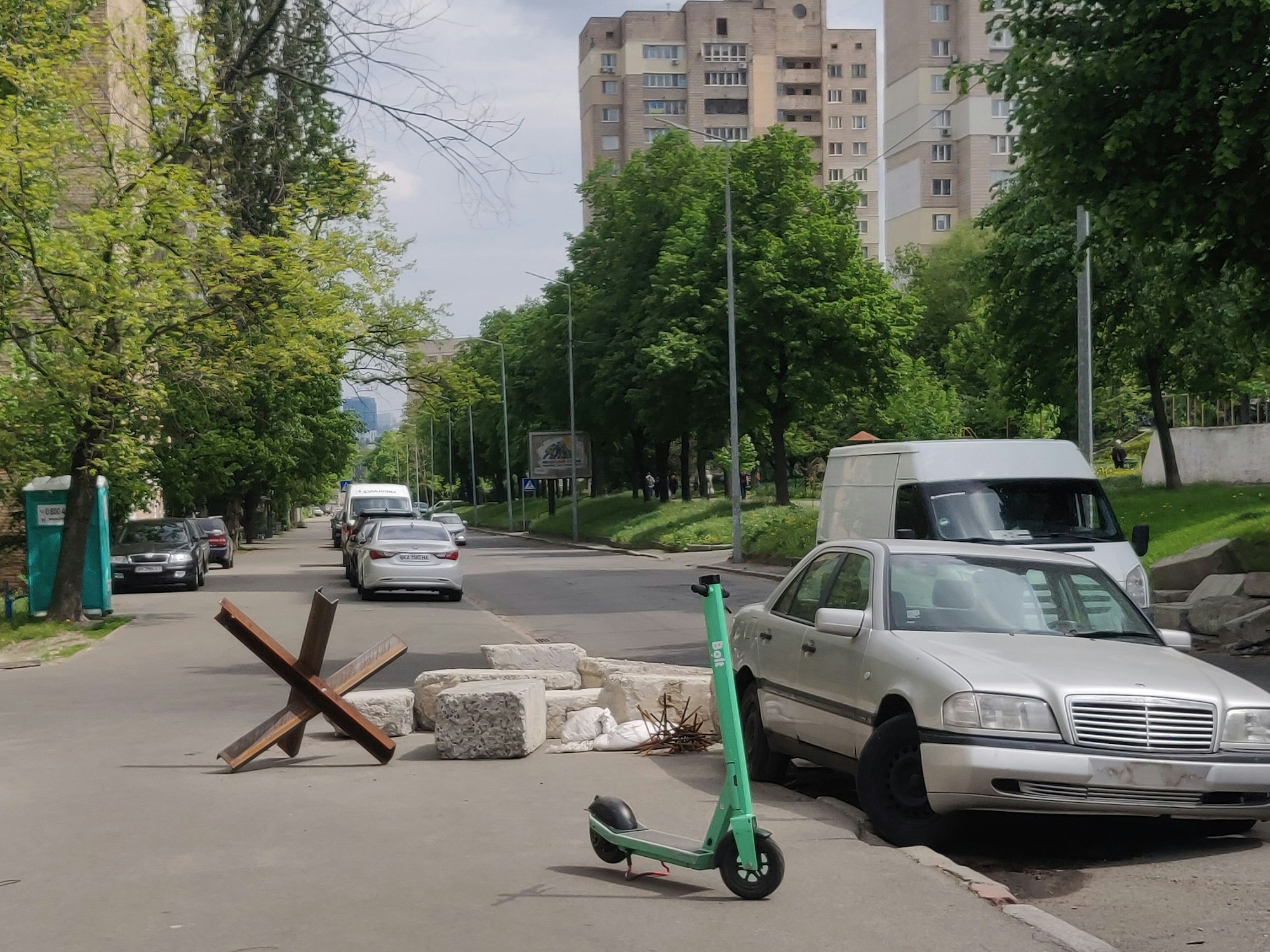 Steinklötze liegen auf dem Boden, neben einer Straße. Davor steht ein E-Scooter.