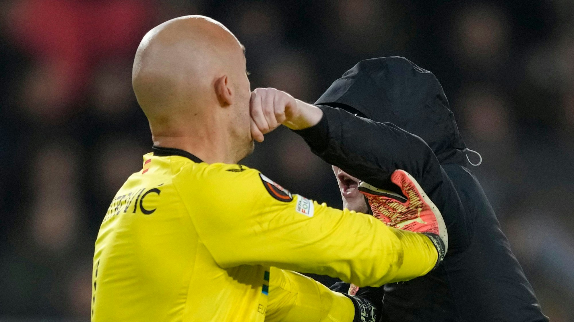 Torwart Marko Dmitrovic vom FC Sevilla wehrt sich am 23. Februar 2023 gegen einen Fan der PSV Eindhoven, der den Platz gestürmt hat.