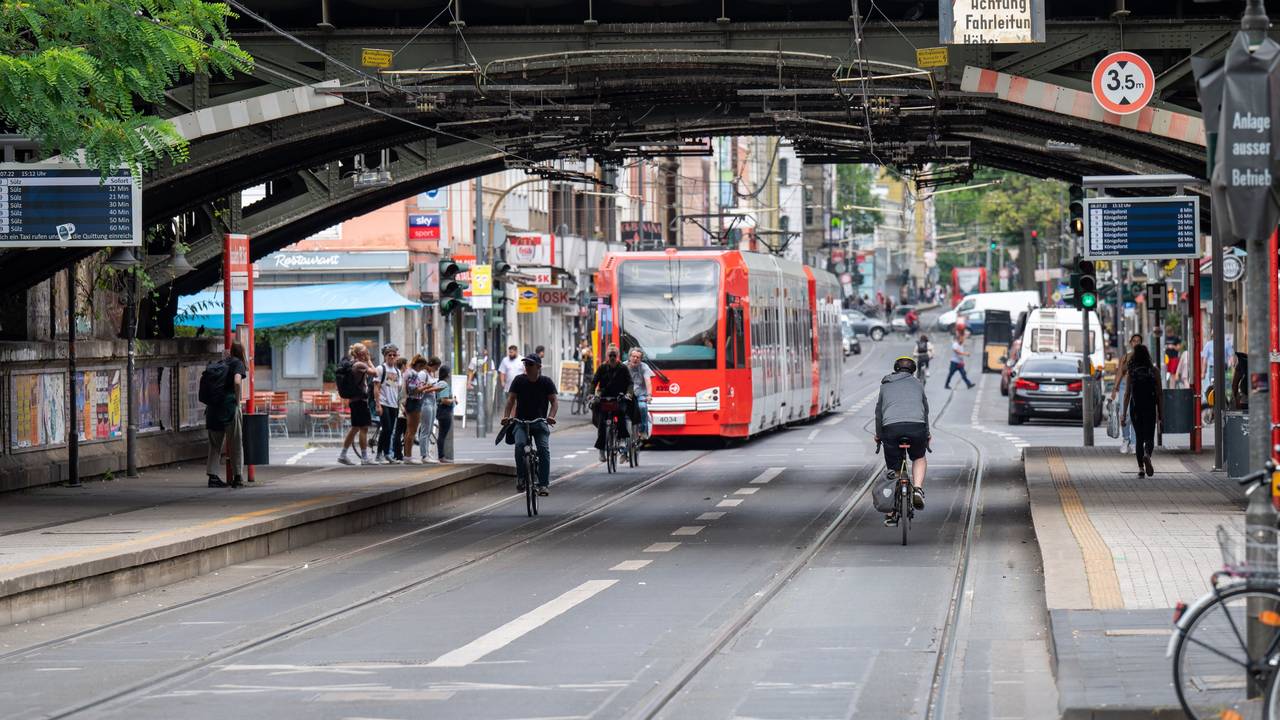 Eine KVB-Bahn der Linie fährt durch eine Unterführung am Bahnhof Süd. Vor der Bahn sind einige Radfahrende unterwegs.