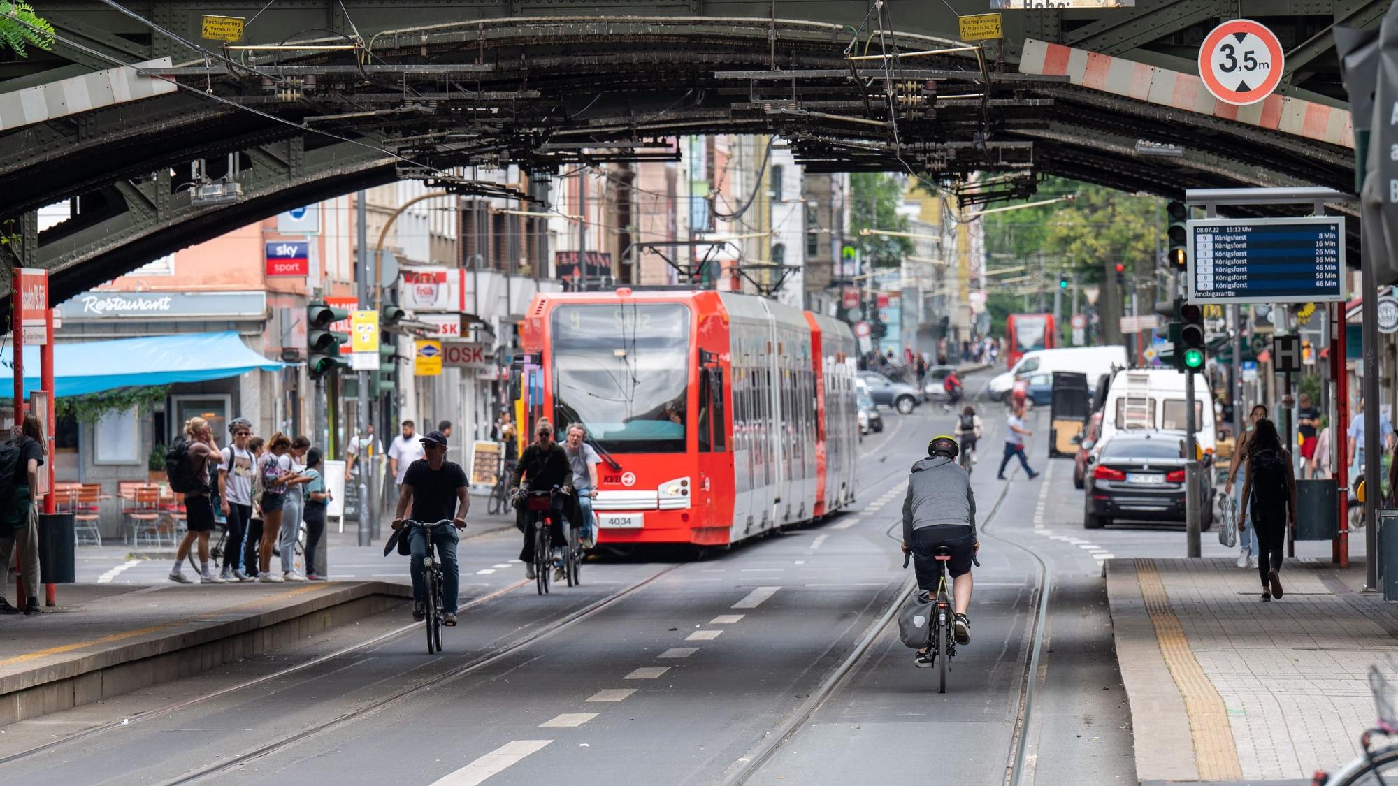Eine KVB-Bahn der Linie fährt durch eine Unterführung am Bahnhof Süd. Vor der Bahn sind einige Radfahrende unterwegs.