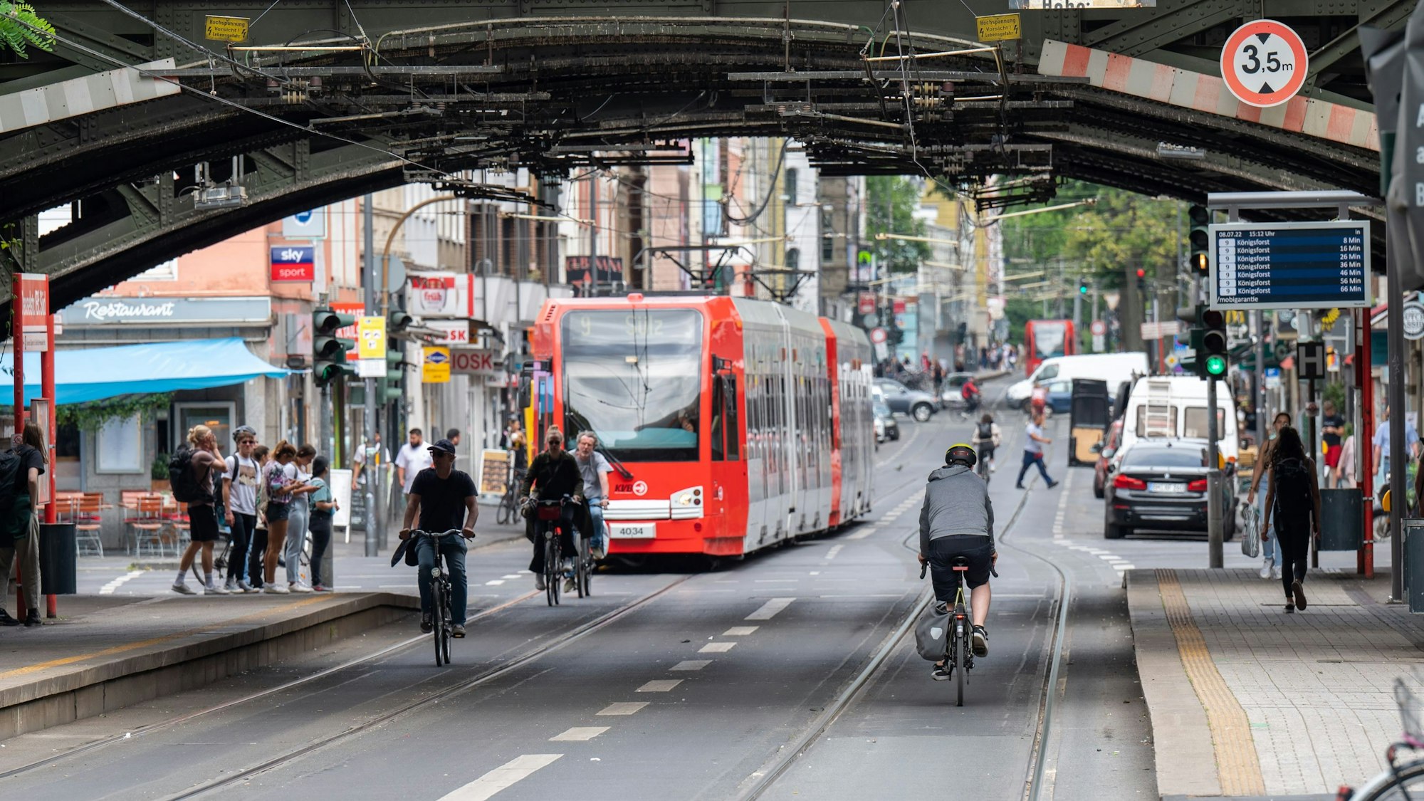 Eine KVB-Bahn der Linie fährt durch eine Unterführung am Bahnhof Süd. Vor der Bahn sind einige Radfahrende unterwegs.