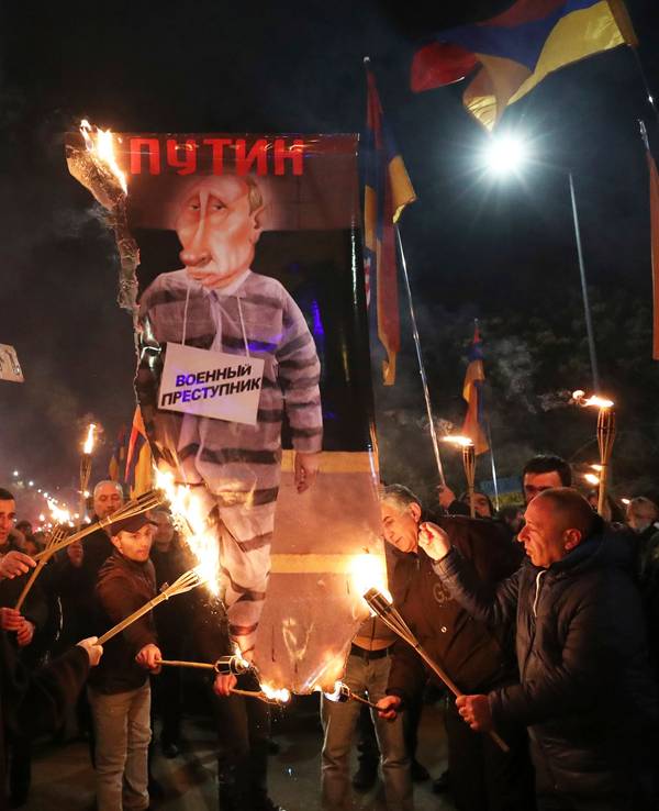 Menschen verbrennen ein Anti-Putin-Plakat mit der Aufschrift «Kriegsverbrecher» während einer Kundgebung zum ersten Jahrestag der russischen Invasion in der Ukraine. Die russische Armee hatte die Ukraine am 24.02.2022 überfallen. +++ dpa-Bildfunk +++