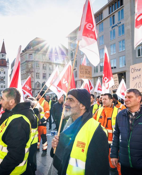 Menschen mit Verdi-Flaggen und Westen protestieren bei einem Streik für mehr Lohn.