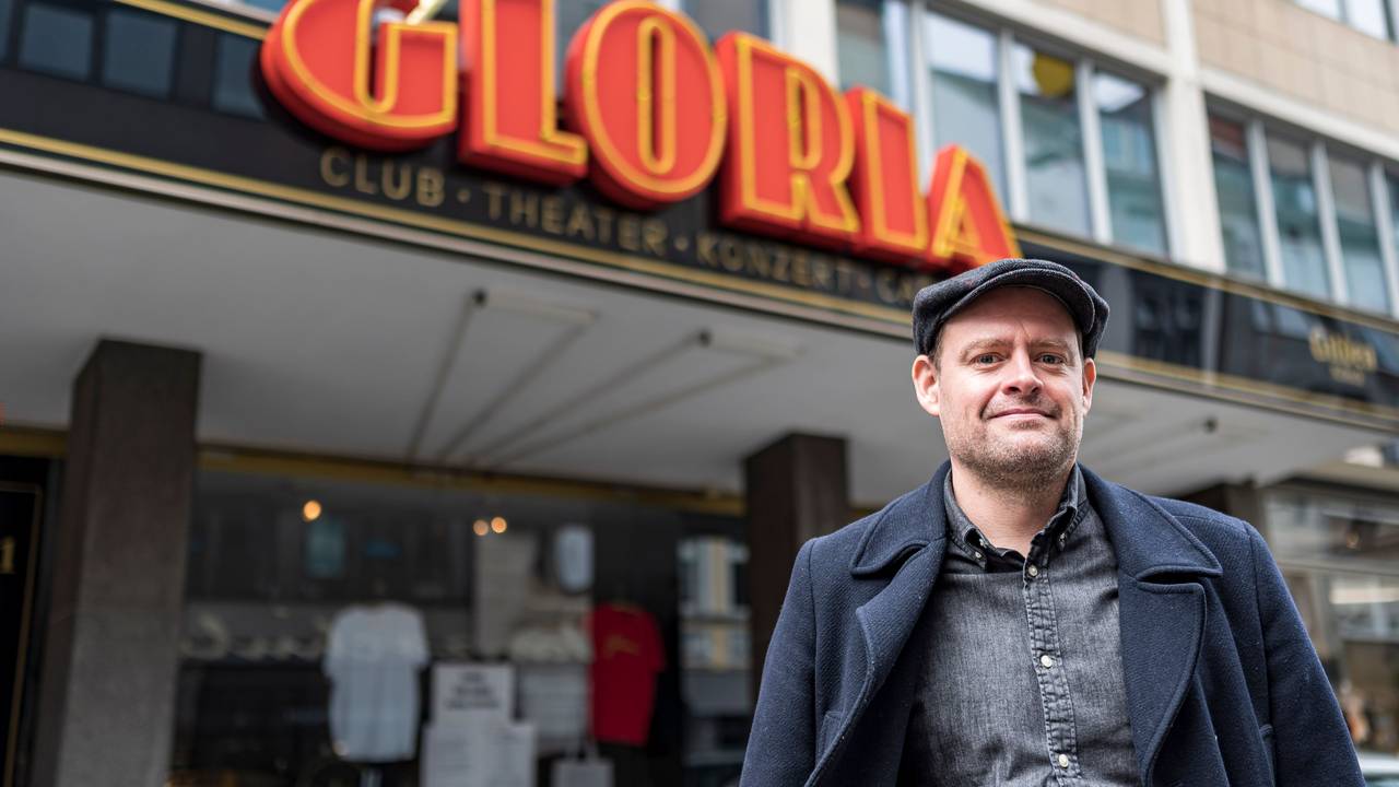 Komiker Max Giermann steht vor dem Gloria in Köln und lacht in die Kamera.
