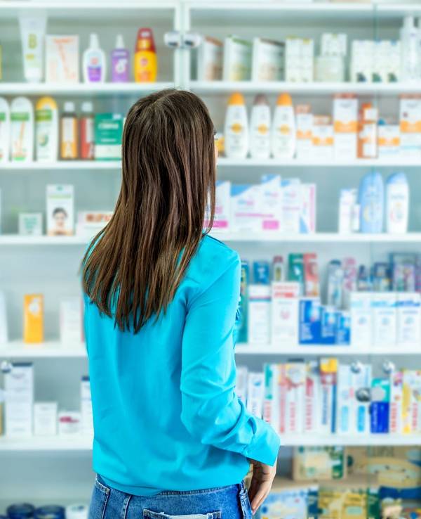 Frau steht vor Regal mit Drogerieprodukten