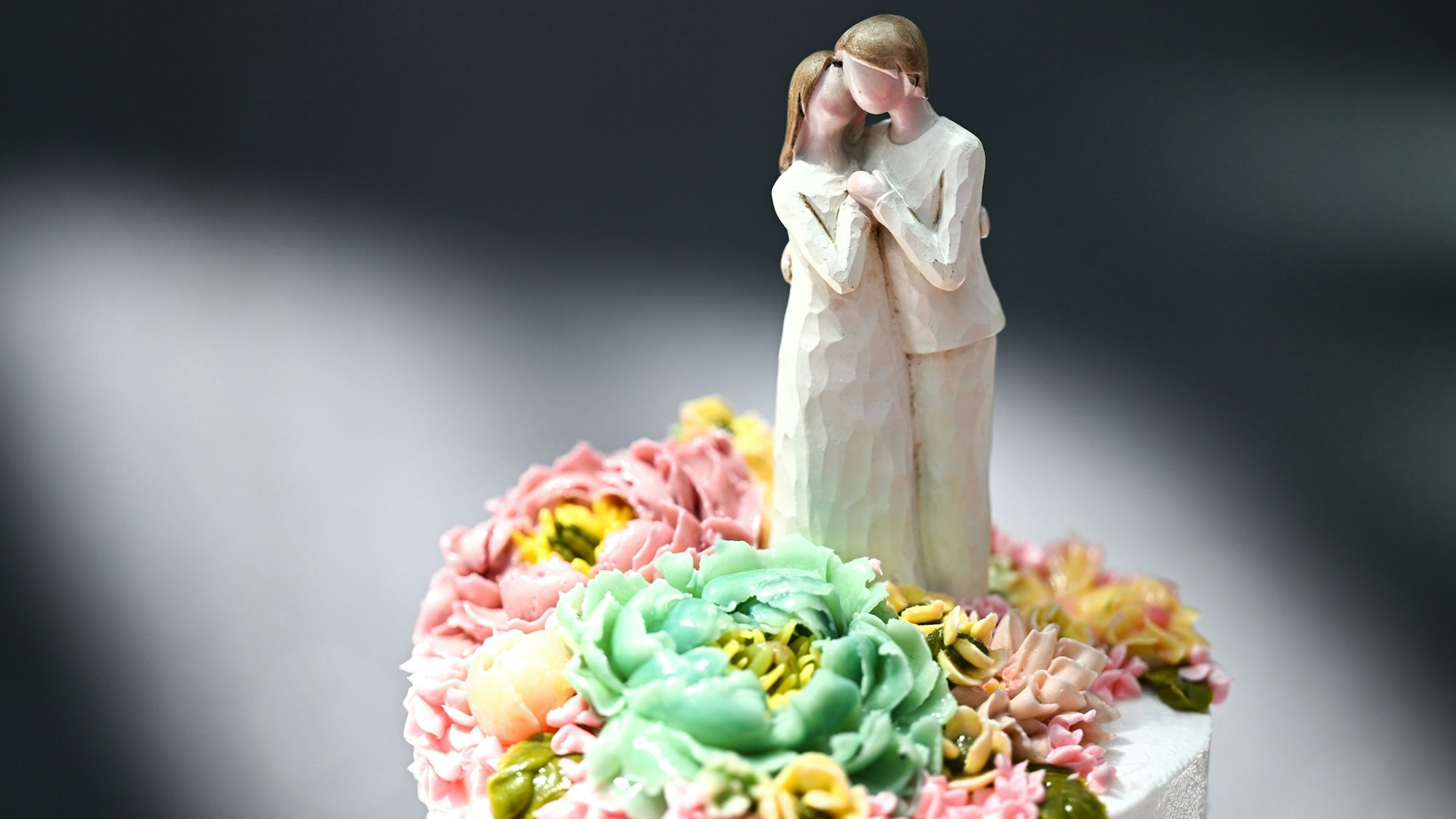 Ein Brautpaar-Figur steht auf einer Hochzeitstorte.