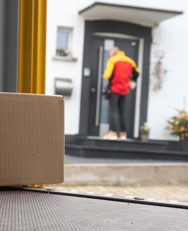 Ein DHL-Mitarbeiter liefert ein Paket aus.