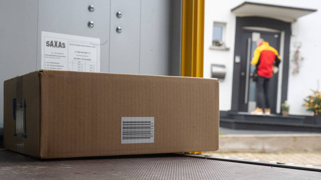 Ein DHL-Mitarbeiter liefert ein Paket aus.