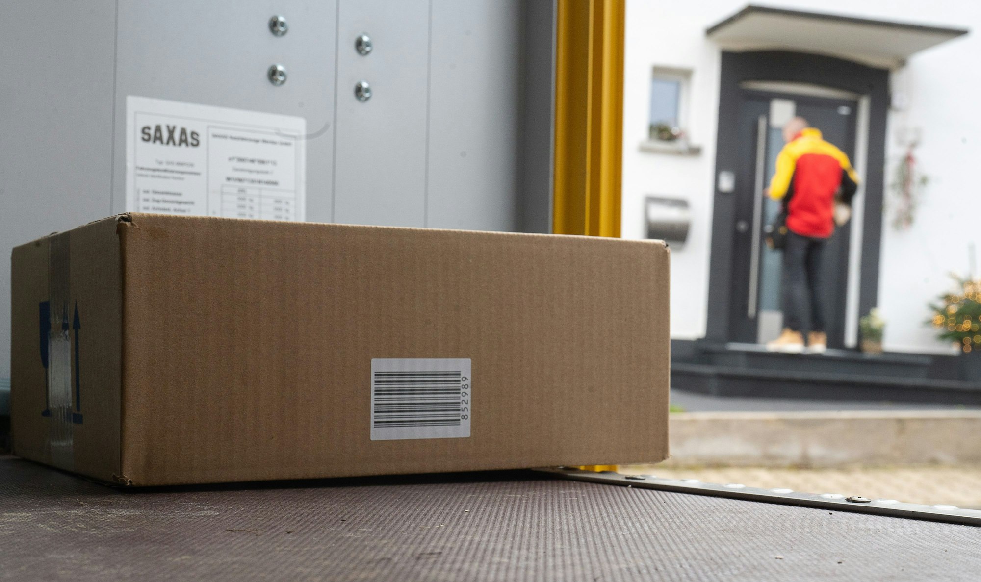Ein DHL-Mitarbeiter liefert ein Paket aus.