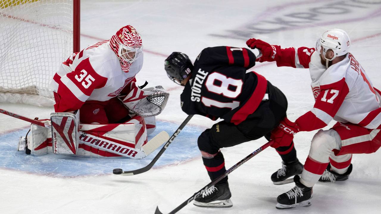 Detroit Red Wings-Verteidiger Filip Hronek (r.) verfolgt Ottawa Senators-Linksaußen Tim Stützle (M.), der den Puck auf Red Wings-Torwart Ville Husso schießt