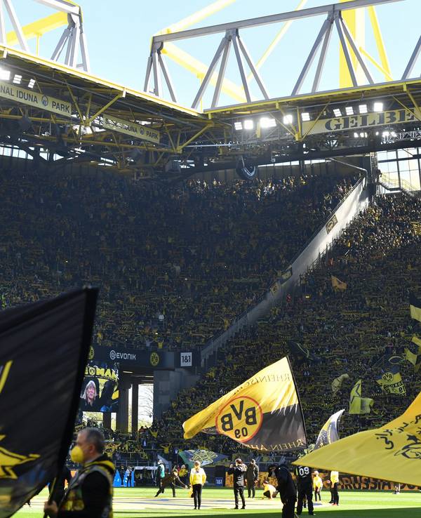 Ein Blick in den Signal-Iduna-Park beim BVB-Heimspiel gegen den VfL Wolfsburg. Auf dem Rasen werden mehrere Fahnen geschwenkt.