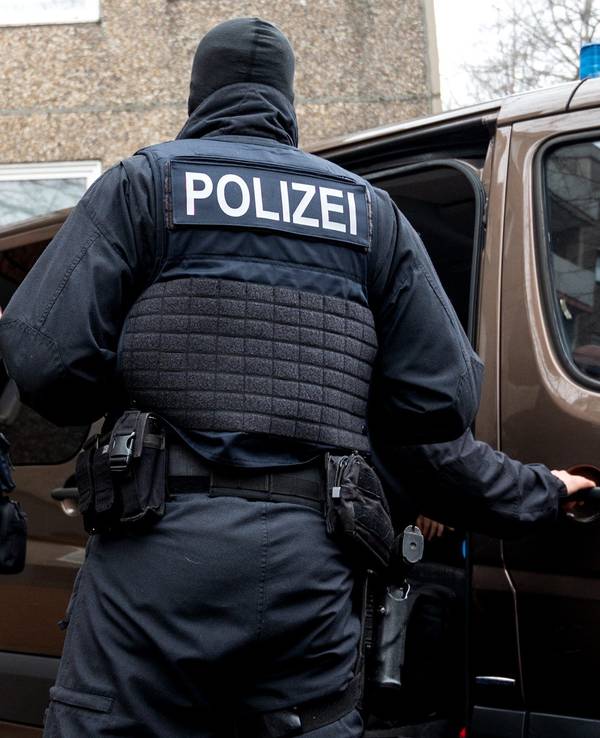 Einsatzkräfte der Polizei stehen vor einem Mehrfamilienhaus.