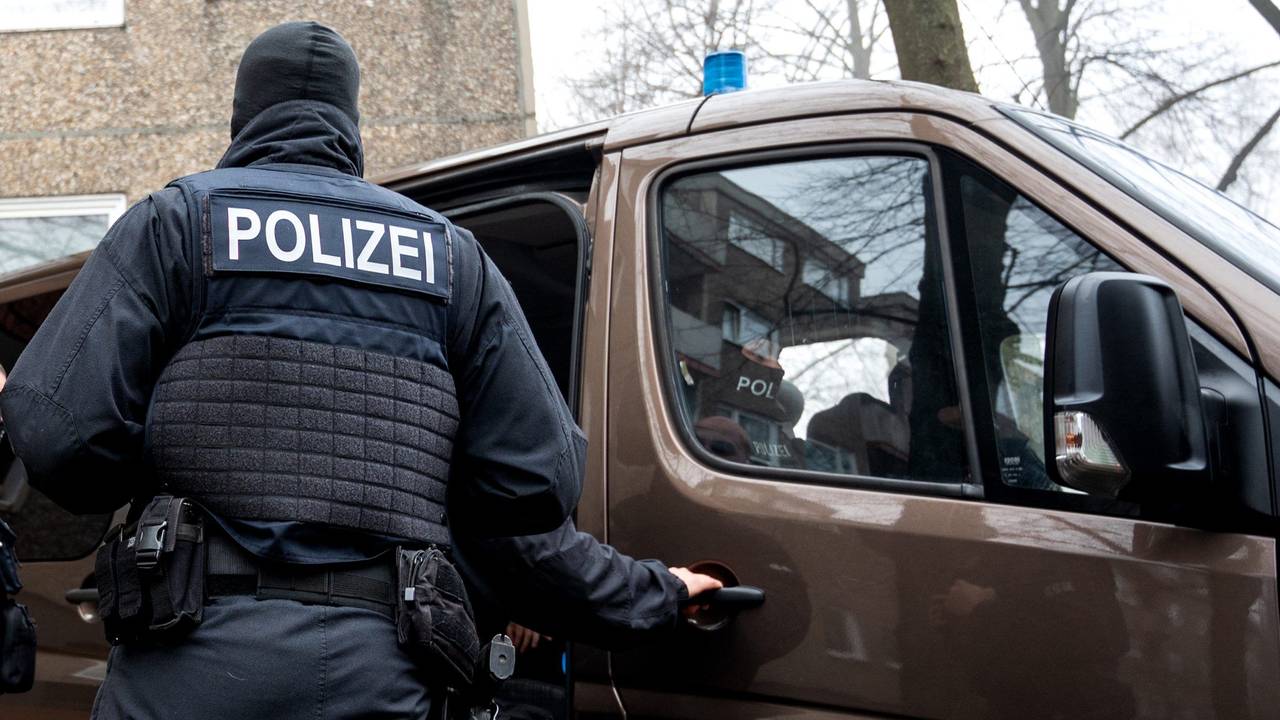 Einsatzkräfte der Polizei stehen vor einem Mehrfamilienhaus.