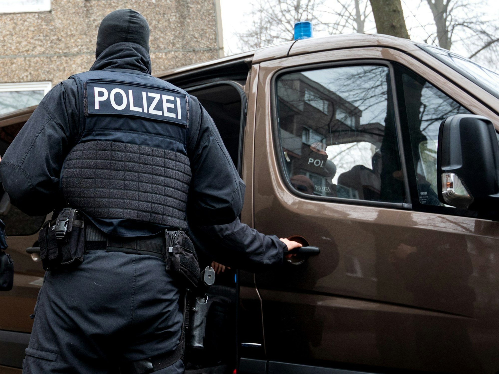 Einsatzkräfte der Polizei stehen vor einem Mehrfamilienhaus.