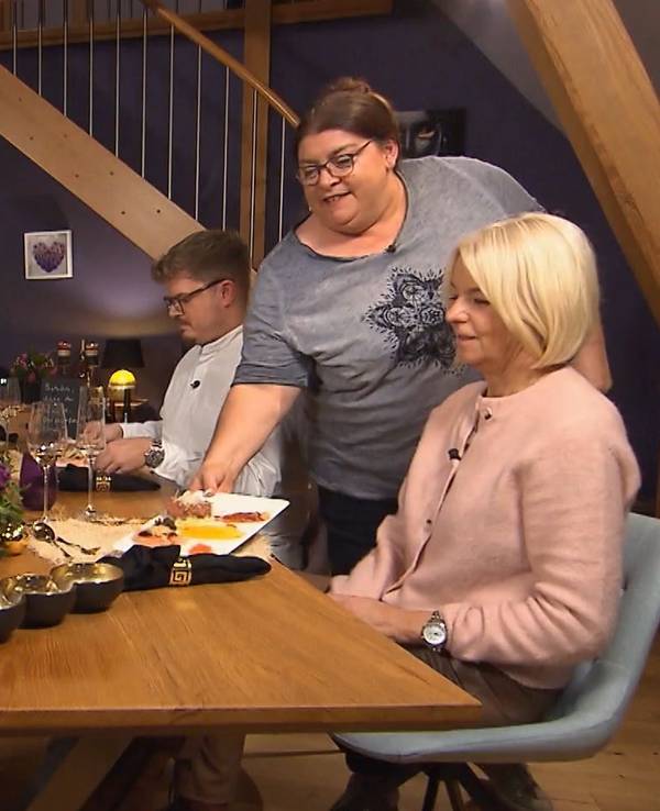 Die Kandidaten sitzen gemeinsam am Tisch, während Nicole das Dessert serviert.