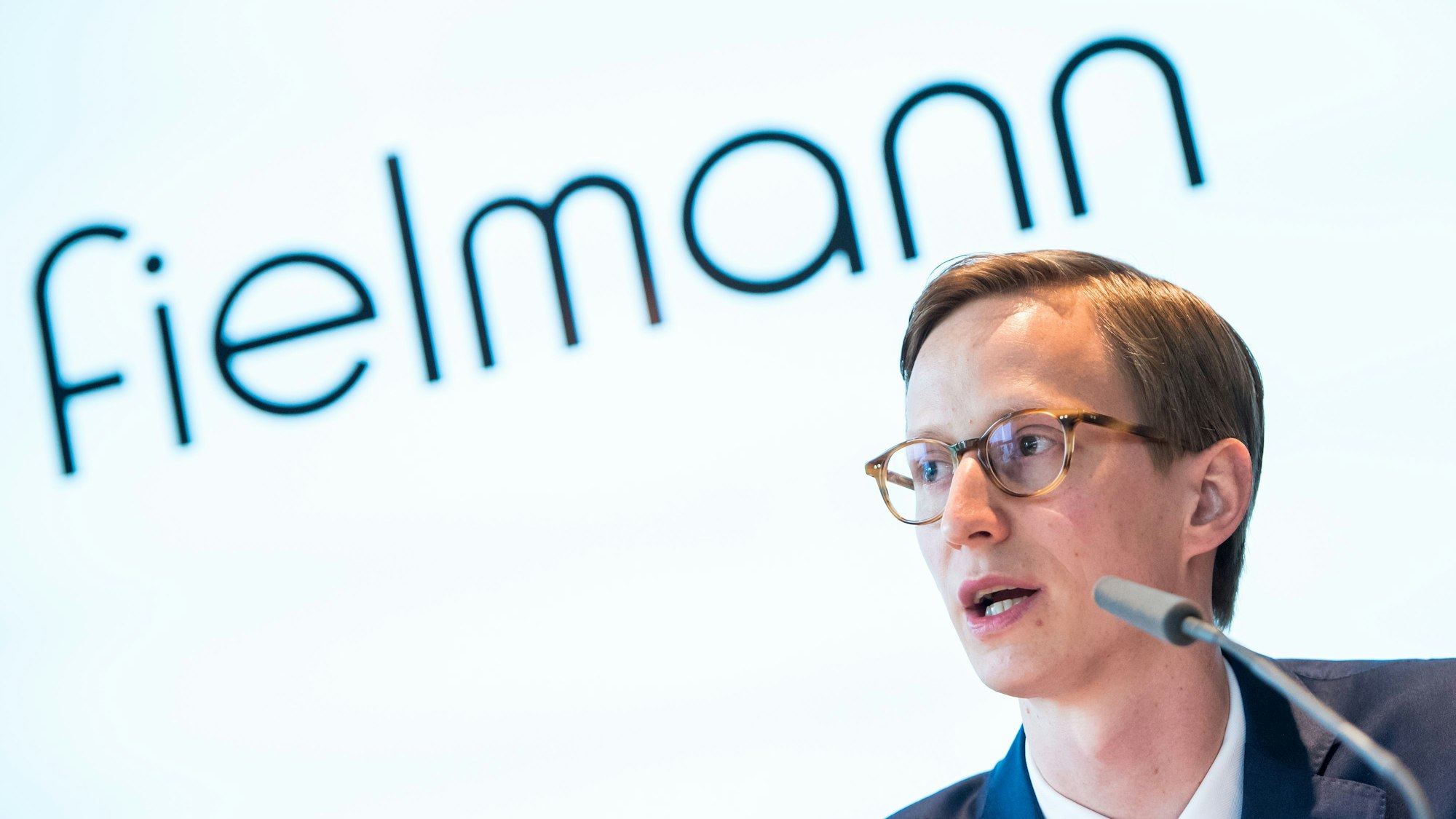 Marc Fielmann spricht bei der Bilanz-Pressekonferenz vor dem Logo des Unternehmens.