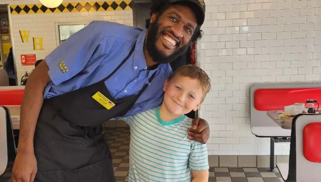 Devonte und Kayzen stehen nebeneinander und halten sich im Arm. Beide lachen in die Kamera.