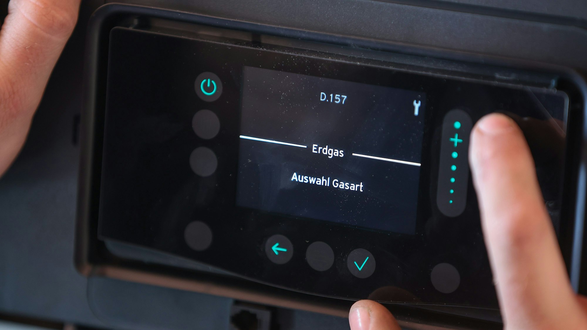 Ein Mitarbeiter einer Sanitär- und Heizungsbaufirma installiert eine moderne Gasbrennwerttherme in einem Einfamilienhaus.