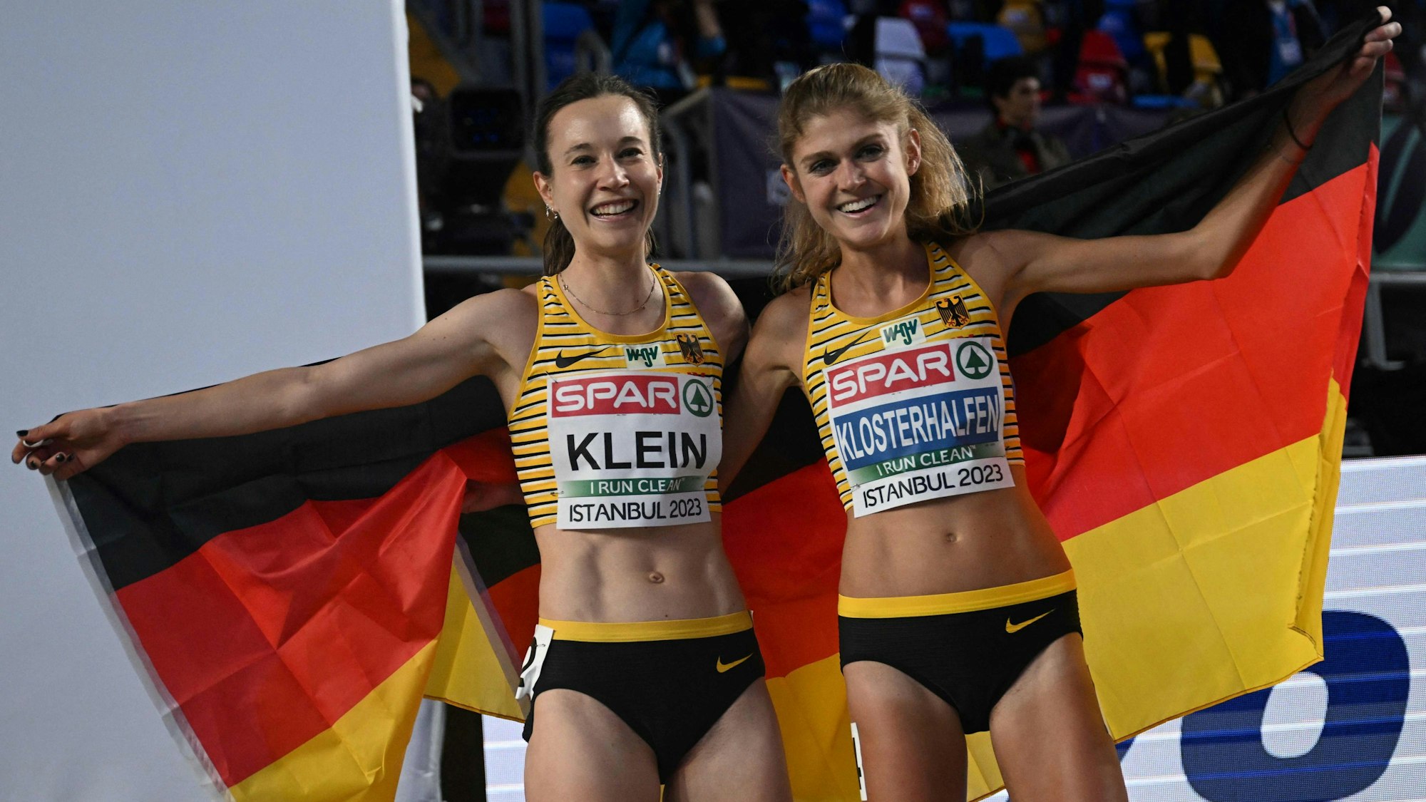 Hanna Klein und Konstanze Klosterhalfen feiern den deutschen Doppelsieg bei der Hallen-EM in Istanbul gemeinsam mit einer Deutschland-Fahne.