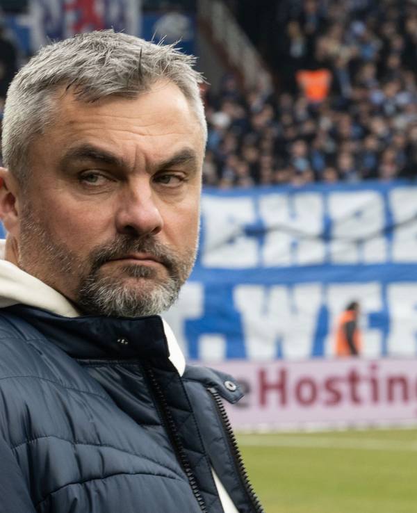 Thomas Reis steht bei seiner Rückkehr ins Ruhrstadion des VfL Bochum am Spielfeldrand. Im Hintergrund hängt ein beleidigendes Plakat gegen den Trainer von Schalke 04.