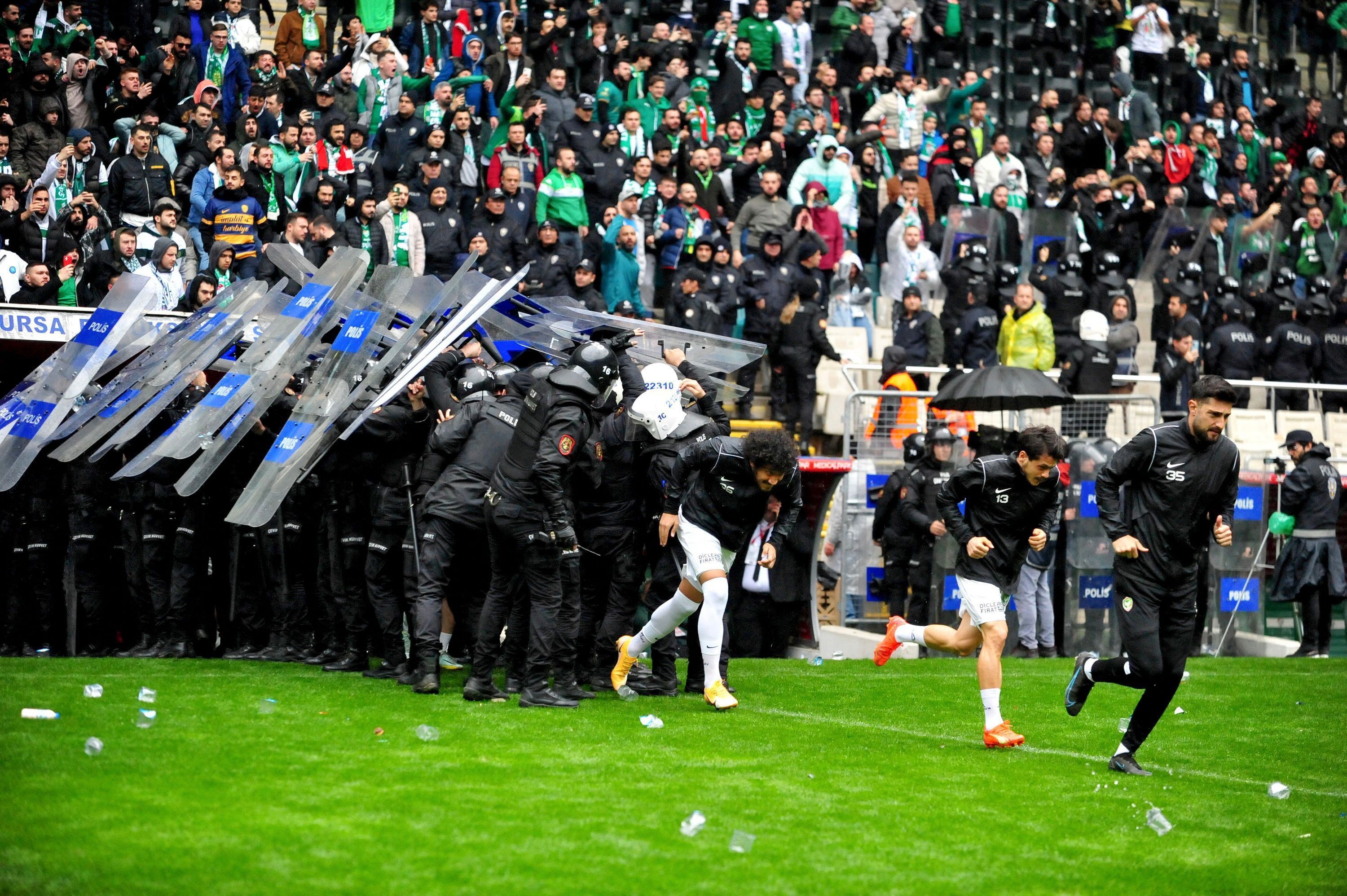 Die Polizei versucht mit Schutzwänden die Spieler von Amedspor vor geworfenen Gegenständen zu schützen.