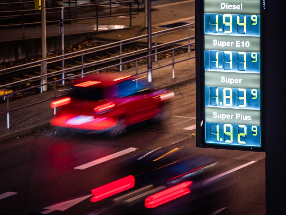 Autos fahren am frühen Morgen an einer Preistafel einer Tankstelle vorbei.