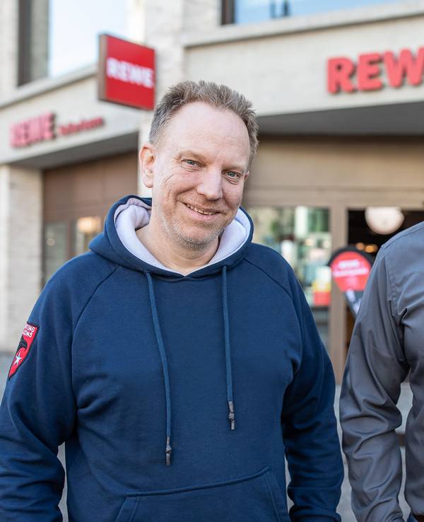 Zwei Männer stehen vor einem neuen Rewe in Köln. Dort wurde ein Teil der historischen Stadtmauer gefunden.