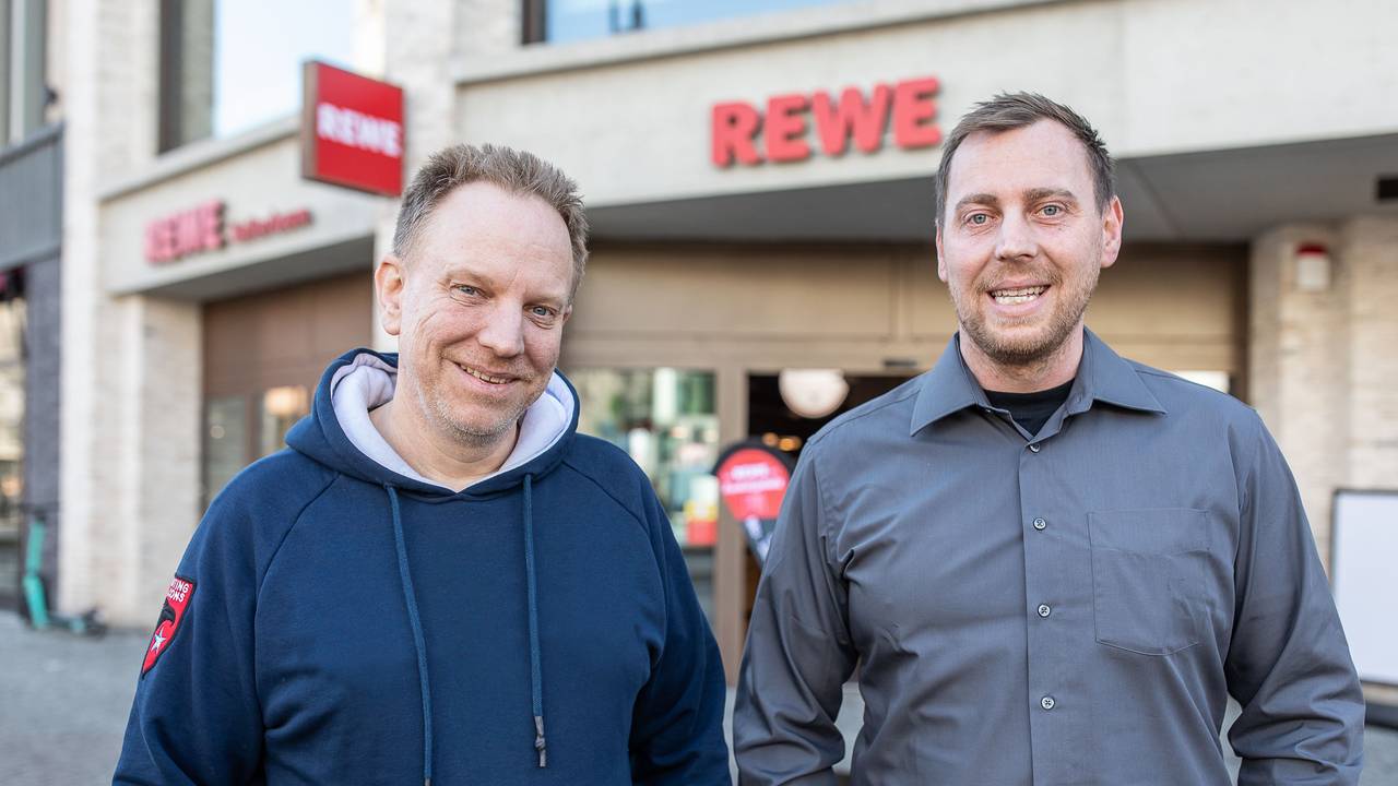 Zwei Männer stehen vor einem neuen Rewe in Köln. Dort wurde ein Teil der historischen Stadtmauer gefunden.
