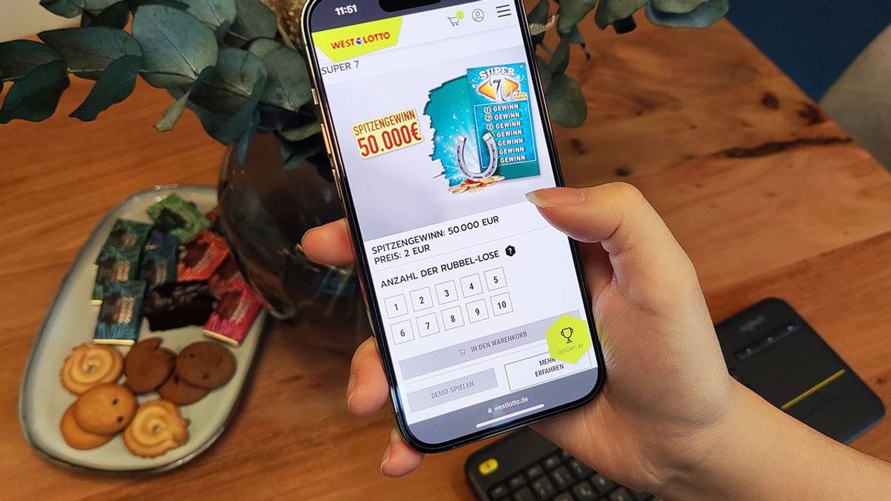 Weibliche Hand hält Smartphone in der Hand, auf dem WestLotto Rubbellose geöffnet sind.