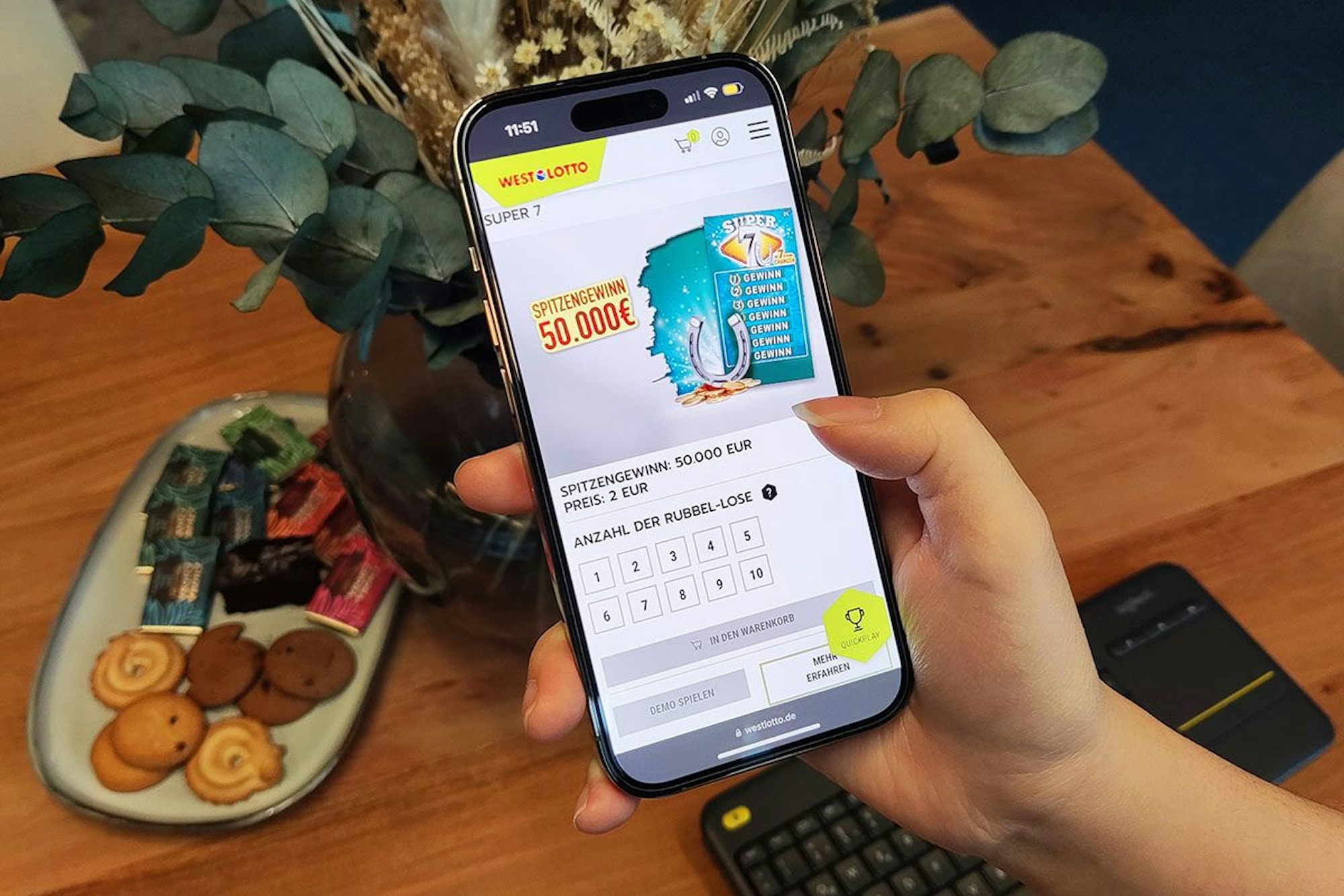 Weibliche Hand hält Smartphone in der Hand, auf dem WestLotto Rubbellose geöffnet sind.