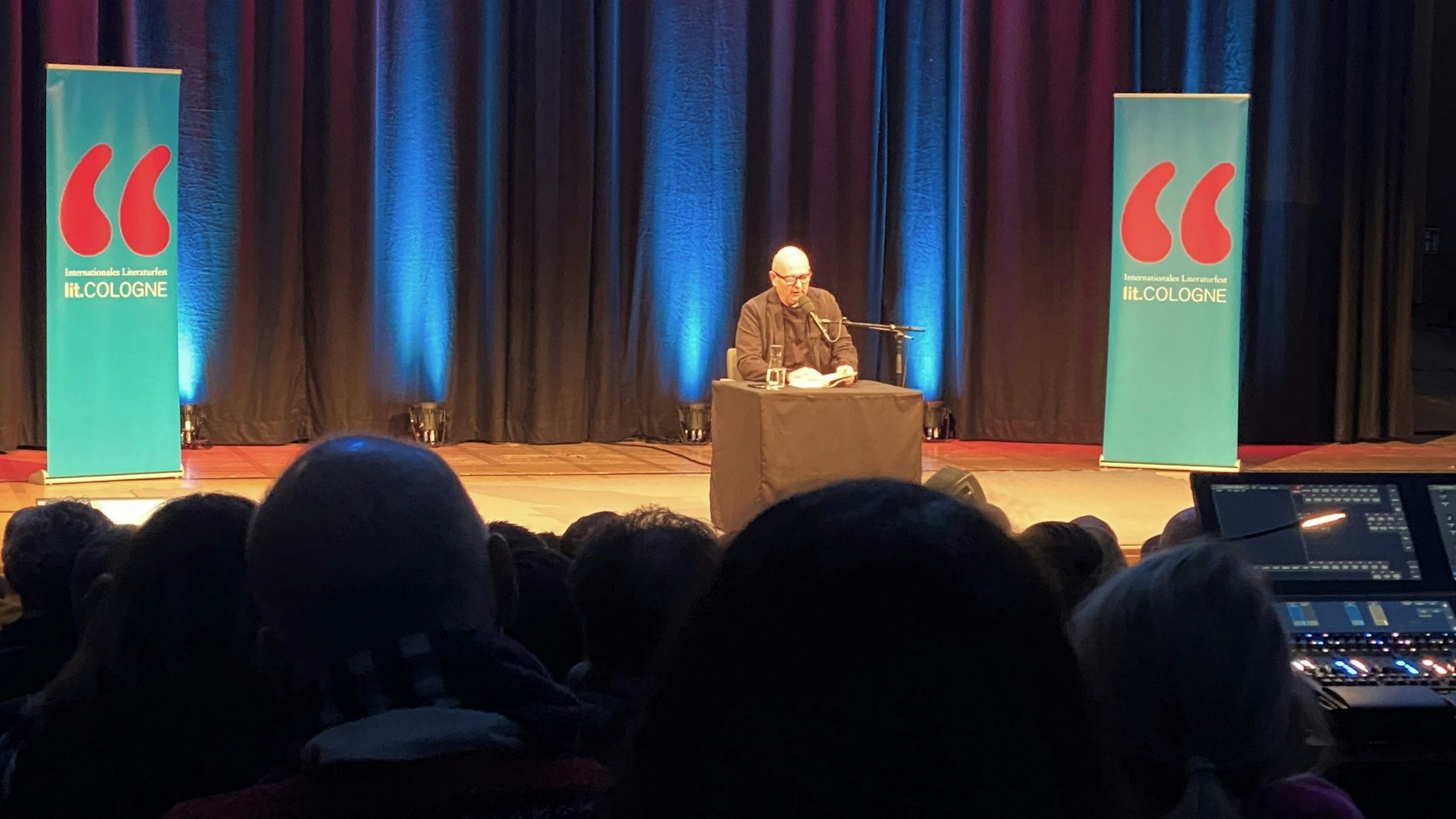 Frank Goosen sitzt bei seinem Auftritt auf der Lit.Cologne an einem Tisch auf der Bühne.