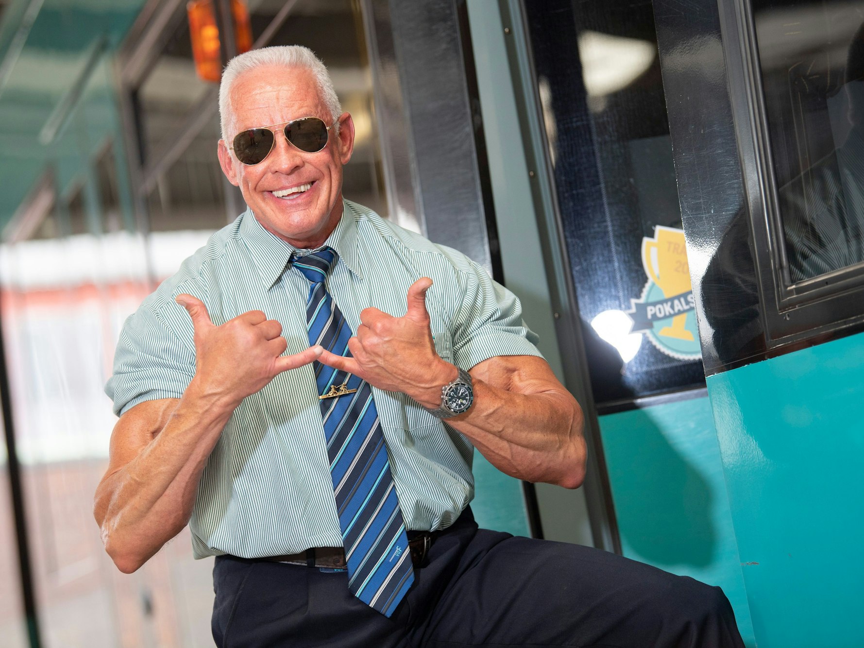 Der als „Bahnbabo“ bekannte Peter Wirth posiert mit dem „Babo-Gruß“ an einer Straßenbahn.