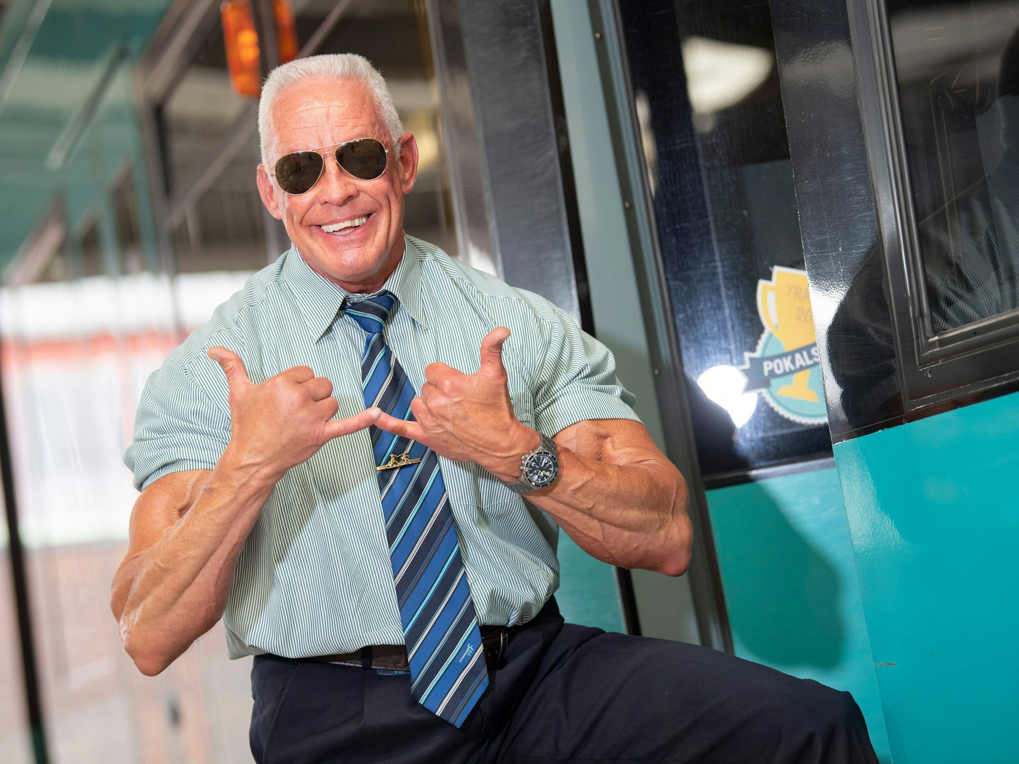 Der als „Bahnbabo“ bekannte Peter Wirth posiert mit dem „Babo-Gruß“ an einer Straßenbahn.